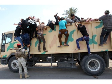 Iraqi men who volunteered to join the fight against a major offensive by jihadists in northern Iraq climb on an army truck outside a recruiting center in the capital Baghdad on June 13, 2014. Iraqi forces clashed with militants advancing on the city of Baquba, just 60 kilometres (40 miles) north of Baghdad, as an offensive spearheaded by jihadists drew closer to the capital.