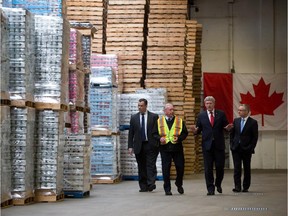 Minister of Industry James Moore, from left to right, Canadian Fishing Company vice-president of operations Rick Pughe, Prime Minister Stephen Harper and Minister of International Trade Ed Fast walk through the company's warehouse where salmon is canned and other seafood products are distributed  in Richmond, B.C., on Wednesday March 12, 2014. The company exports to South Korea, with whom Canada has signed a trade agreement.