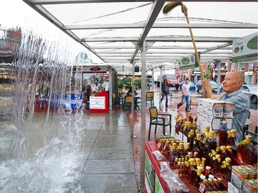 John Hazekamp pushes water off the roof of the Maple Country Sugar Bush stall in the Byward Market as the region was hit with a significant amount of rain on Tuesday. Photo taken at 14:00 on June 24, 2014.