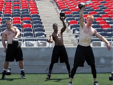 Jon Gott, left, strains to pick up the weight ball during some strength training with teammates after practice. The Ottawa Redblacks held their first practice ever at the new TD Place stadium at Lansdowne Park Friday, June 27, 2014.