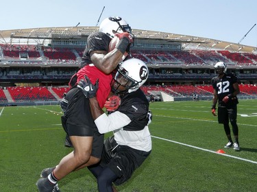 Jovon Johnson keeps the ball under a tight grip during a tackling practice at the new stadium. The Ottawa Redblacks held their first practice ever at the new TD Place stadium at Lansdowne Park Friday, June 27, 2014.