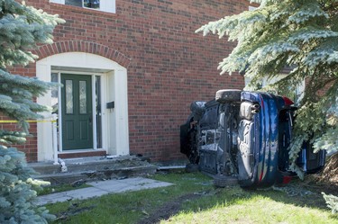 A vehicle lays on its side after it crashed into a house on Steeplechase Drive in Kanata on Sunday, June 15, 2014.