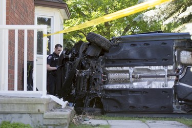 An Ottawa police officer makes notes after a vehicle crashed into a house on Steeplechase Drive in Kanata on Sunday, June 15, 2014.