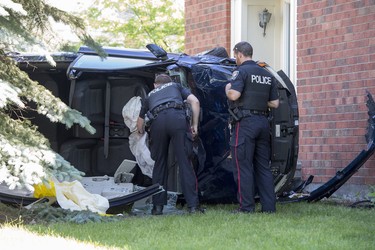 Ottawa police officers inspect a vehicle that  crashed into a house on Steeplechase Drive in Kanata on Sunday, June 15, 2014.