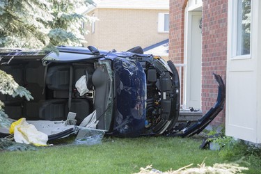 A vehicle with its roof removed lays on its side after it crashed into a house on Steeplechase Drive in Kanata on Sunday, June 15, 2014.