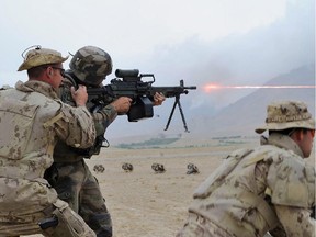 Kabul, Afghanistan. 3 August 2013 - MCpl Joe Wilson, a member of the Roto 3 Quick Reaction Force, assists a member of the Armee de Terre from France, as they take aim with the C9 machine gun during a coalition training session at KMTC on August 3, 2013.