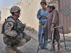 Kandahar, Afghanistan. 7 November 2009 - Since the road improvement project in the village of Deh-e Bagh, a young Afghan boy stricken with Polio has greater mobility allowing him access to the road to greet Lieutenant Pierre-Vincent Daigle as he passes through the village on a patrol.