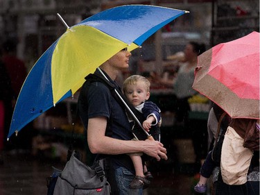 Kyle Browness, with his son Joshua, 16 months, contemplate their next move while visiting the Byward Market with his wife Stephanie and twin daughter Grace (both under the umbrella at right) as the region was hit with a significant amount of rain on Tuesday. Photo taken at 13:59 on June 24, 2014.