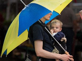 Kyle Browness, with his son Joshua, 16 months, contemplate their next move while visiting the Byward Market with his wife Stephanie and twin daughter Grace as the region was hit with a significant amount of rain on Tuesday. Photo taken at 13:59 on June 24, 2014.