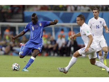 Italy's Mario Balotelli, left, gets in a shot as England's Phil Jagielka, center, and Jordan Henderson, right, defend during the group D World Cup soccer match between England and Italy at the Arena da Amazonia in Manaus, Brazil, Saturday, June 14, 2014.
