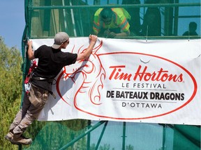 Matt Mulligan hangs precariously while he and Derek Bulmer attach a Dragon Boat banner to scaffolding set up at Mooney's Beach as the annual fund raising festival is about to get underway on Thursday. Photo taken at 10:35 on Tuesday, June 17, 2014.