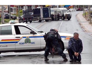 MONCTON, N.B.: June 5, 2014 -- R.C.M.P. officers are at the ready with their weapons as other officer (background) prepare to go in a house during a manhunt for Justin Bourque in Moncton, New Brunswick, on Wednesday, June 5, 2014. The man is suspected of killing three Royal Canadian Mounted Police officers. (John Kenney / THE GAZETTE) ORG XMIT: 50165 ORG XMIT: POS1406051415516966