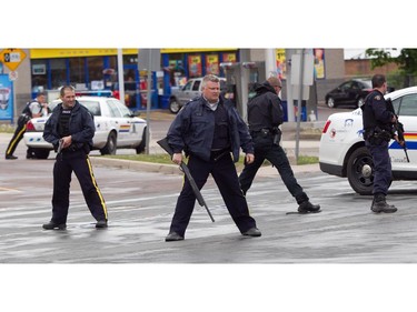 MONCTON, N.B.: June 5, 2014 -- R.C.M.P. officers stand at the ready with their weapons drowns as other officer (unseen down the road) were preparing to go in a house during a manhunt for Justin Bourque in Moncton, New Brunswick, on Wednesday, June 5, 2014. The man is suspected of killing three Royal Canadian Mounted Police officers. (John Kenney / THE GAZETTE) ORG XMIT: POS1406051419556995 ORG XMIT: POS1406051425167041