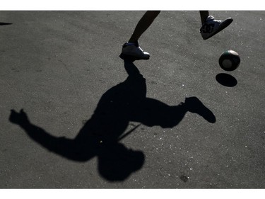 The shadow of Murilo Cretucci, from Sao Paulo, Brazil, is cast on the ground as he plays ball outside Itaquerao Stadium before the start of the World Cup opening match in Sao Paulo, Brazil, Thursday, June 12, 2014.