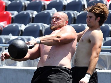 Nate Menkin, left, and other players hoist huge weights after practice for strength training. The Ottawa Redblacks held their first practice ever at the new TD Place stadium at Lansdowne Park Friday, June 27, 2014.
