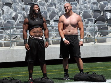 Nate Menkin, right, takes a break with a teammate after hauling bags of sand back and forth across the field after practice for strength training. The Ottawa Redblacks held their first practice ever at the new TD Place stadium at Lansdowne Park Friday, June 27, 2014.