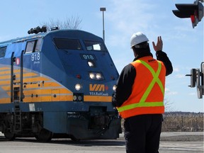 OTTAWA, ON. APRIL 11, 2014 --- A VIA employee waves at the oncoming train after manually stopping traffic at the Woodroffe railway crossing in Barrhaven Friday. However, after the train passed, the arms and signals malfunctioned, almost landing on oncoming traffic, before lifting up again.  Barrhaven city councillor Jan Harder checks out five  railway crossings in Barrhaven - many of which have been plagued by mechanical problems and safety issues. (Julie Oliver/Ottawa Citizen) #116718. CITY.