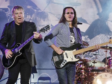 Geddy Lee, (C),  Alex Lifeson (L), and Neil Peart on drums (R) of Rush perform as Bluesfest continues Monday evening on the grounds of the Canadian War Museum.