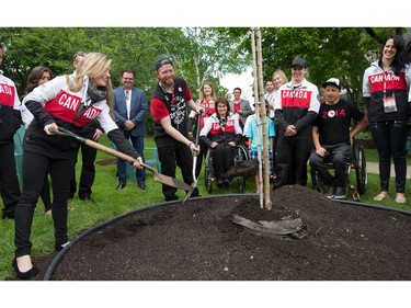 Para-snowboarder John Leslie (C) and Olympic figure skater Paige Lawrence (L) help plant a tree as Manoir Ronald McDonald House Ottawa welcomed Canadian Olympians and Paralympians to the House as part of the 2014 Celebration of Excellence for the athletes and the 30th anniversary of the House. John Leslie was a resident at Ronald McDonald House 10 years ago when he lost a leg to cancer.