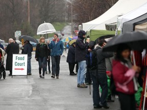 People cover themselves with umbrellas as they make their way through The Farmers��� Market in Brewer Park on Sunday, May 4, 2014. (Cole Burston/Ottawa Citizen)