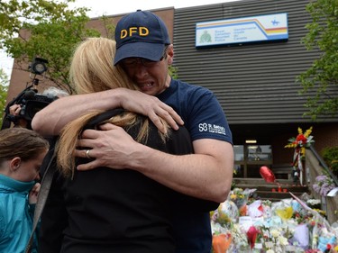 People hug outside RCMP headquarters in Moncton, N.B., on Friday, June 6, 2014. RCMP say a man suspected in the shooting deaths of three Mounties and the wounding of two others in Moncton was unarmed at the time of his arrest early Friday and was taken into custody without incident.