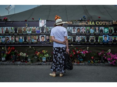 A woman looks at photographs of anti-government protesters killed during the Euromaidan demonstrations at a makeshift memorial on Independence Square on June 7, 2014 in Kiev, Ukraine.