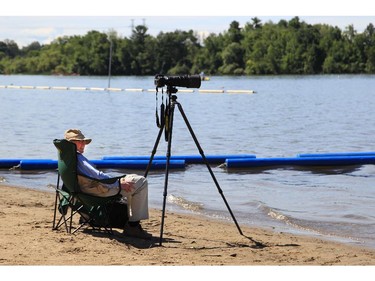 Photographer Bob McAlpine takes a break between races at the Dragon Boat Festival at Mooney's Bay on Saturday.