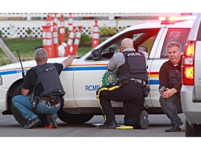 Police officers take cover behind their vehicles in Moncton, New Brunswick, on Wednesday June 4, 2014.