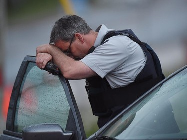 An RCMP officer rests his head at a roadblock in Moncton, N.B. on Thursday, June 5, 2014. Three RCMP officers were killed and two injured by a gunman wearing military camouflage and wielding two guns on Wednesday. Police have identified a suspect as 24-year-old Justin Bourque of Moncton.