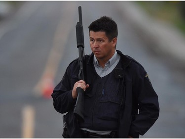 An RCMP officer stands at a roadblock in Moncton, N.B. on Thursday, June 5, 2014. Three RCMP officers were killed and two injured by a gunman wearing military camouflage and wielding two guns on Wednesday. Police have identified a suspect as 24-year-old Justin Bourque of Moncton.