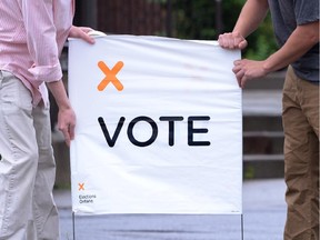 Poll station workers place a vote sign in preparation for voters on election day in Carleton Place, Ont. on Thursday June 12, 2014.