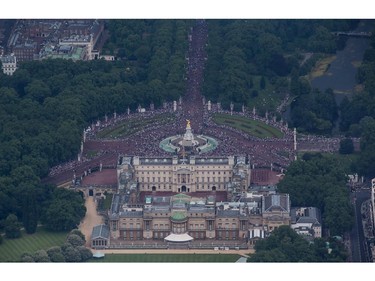 People gather in the Mall to watch a fly past over Buckingham Palace as part of Her Majesty The Queen's Birthday Flypast during Trooping the Colour on June 14, 2014 in London, England.