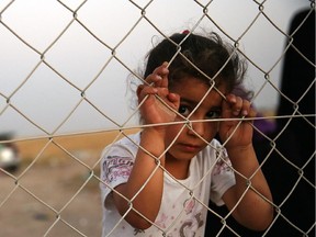 An Iraqi child waits with her family outside of a temporary displacement camp for Iraqis caught-up in the fighting in and around the city of Mosul on June 26, 2014 in Khazair, Iraq.