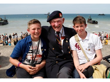 World War II veteran Reg Blake, 88, from London, England, of the Royal Marines, who landed in Lion-sur-Mer on the 6 June 1944, poses with high school students Simon Legouge-Duval, left, and Adrien Sublin, on the beach of Arromanches, France, Friday, June 6 , 2014.  World leaders and veterans gathered by the beaches of Normandy, northern France on Friday to mark the 70th anniversary of the World War II D-Day landings.