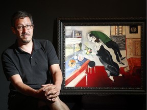 Saw Gallery curator, Jason St-Laurent, sits beside a painting in the style of Marc Chagall by Graciela Montealegre.