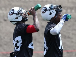 Seth Williams #23 (L) and Eddie Elder #18 (R), of the Ottawa Redblacks cool off from the heat with water during a practice at TD Place stadium in Ottawa on June 29, 2014.