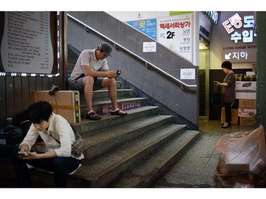 People use their mobile phones in a market in Seoul on June 13, 2014. South Korea's central bank on June 12 kept key interest rates unchanged for the 13th consecutive month as Asia's fourth-largest economy shows signs of steady recovery. South Korea's export-led economy is forecast to accelerate as demand in industrialised nations recover.