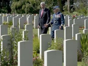 Canadian Prime Minister Stephen Harper speaks with Major-General Richard Rohmer as he walks through the Canadian military cemetery Friday June 6, 2014 in Beny-sur-Mer, France.