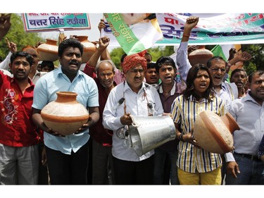 Supporters of Congress party shout slogans as they carry a bucket and earthen pots outside the ruling Bharatiya Janata Party (BJP) office during a protest against long power cuts and water shortage  in New Delhi, India, Friday, June 13, 2014. Severe heat wave conditions have prevailed in the northern plains of the country leading to power and water shortage in several cities.