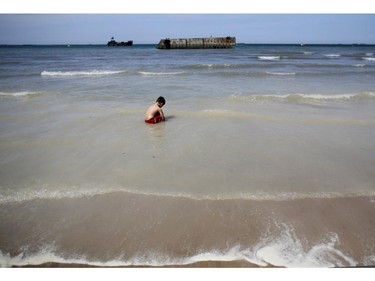 BAYEUX, FRANCE - JUNE 06:  A boy plays in the sea in front of the remains of the Mulbery Harbour at Arrowmanches-Les-Bains during D-Day 70 Commemorations on June 6, 2014 near Bayeux, France. Friday 6th June is the 70th anniversary of the D-Day landings which saw 156,000 troops from the allied countries including the United Kingdom and the United States join forces to launch an audacious attack on the beaches of Normandy, these assaults are credited with the eventual defeat of Nazi Germany. A series of events commemorating the 70th anniversary are planned for the week with many heads of state travelling to the famous beaches to pay their respects to those who lost their lives