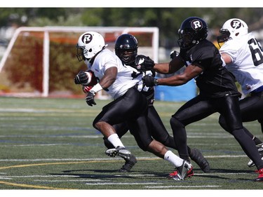 The Ottawa RedBlacks #22 Eric O'Neal is tackled during an intrasquad game at the Mont-Bleu Sports Complex in Gatineau on Saturday, June 7, 2014.