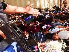 This image posted on a militant website on Saturday, June 14, 2014, which has been verified and is consistent with other AP reporting, appears to show militants from the al-Qaida-inspired Islamic State of Iraq and the Levant (ISIL) with captured Iraqi soldiers wearing plain clothes after taking over a base in Tikrit, Iraq. The Islamic militant group that seized much of northern Iraq has posted photos that appear to show its fighters shooting dead dozens of captured Iraqi soldiers in a province north of the capital Baghdad. Iraq's top military spokesman Lt. Gen. Qassim al-Moussawi confirmed the photos' authenticity on Sunday and said he was aware of cases of mass murder of Iraqi soldiers.