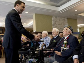 WWll veteran Ross Baker, centre, refuses to shake PC leader Tim Hudak's hand as Hudak greets with seniors and WWll veterans while taking part in D Day celebrations at the Chartwell Scarlett Heights Retirement Residence during a campaign stop in Toronto on Friday, June 6, 2014. Baker says this day is for veterans not politicians.