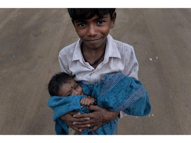 TOPSHOTS An Indian street child poses with his sister in his arms as raindrops began falling in New Delhi on June 12, 2014. Rain fell in the Indian capital following a spell of record hot weather, bringing down temperatures and increasing humidity ahead of the monsoon season which is expected to be "deficient", according to the met department.