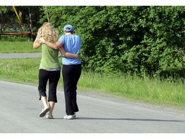 Two woman who know the victim walk arm in arm past 170 Grey Fox Dr., the scene of a fire and death in Corkery (Ottawa), Sunday, June 8, 2014. A 49-year-old man died outside his home after receiving CPR from firefighters and paramedics.