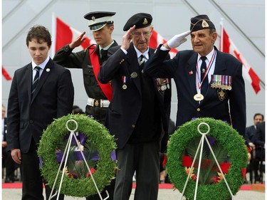 Veterans Paul Bender and Allan Notman salute as Zachary Brown (right to left), representing youth, looks on during a wreath laying ceremony in Ottawa, Friday June 6, 2014 marking the 70th Anniversary of D-Day and the Battle of Normandy.