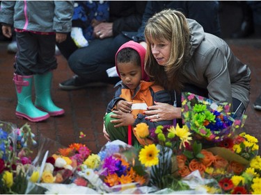 A woman and child participate in a candle light vigil in Moncton, N.B. on Friday, June 6, 2014 to pay respect to the three RCMP officers who were killed and the two injured in a shooting spree on Wednesday. Justin Bourque, 24, is facing three charges of first-degree murder and two charges of attempted murder.