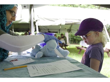 Violet Lowe, 4-1/2, watches as 15-year-old medic Dahlia Migahed makes a plaster cast for Violet's bear, Blue Bear, which suffered a broken leg, at the CHEO Teddy Bear pinic at Rideau Hall on Saturday.