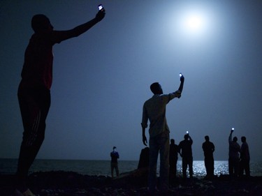 John Stanmeyer, USA, VII for National Geographic, 26 February 2013, Djibouti City, Djibouti. Impoverished African migrants crowd the night shore of Djibouti city, trying to capture inexpensive cell signals from neighboring Somalia—a tenuous link to relatives abroad. For more than 60,000 years our species has been relying on such intimate social connections to spread across the Earth. From the exhibition of World Press Photo winners for 2014 at the Canadian War Museum