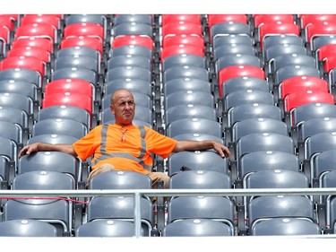 12.21 p.m: Construction worker Jean Saumur takes a short break in the stands to catch some of the action on the field as the Ottawa Redblacks practice at TD Place Stadium at Lansdowne Park on Monday, July 14, 2014.